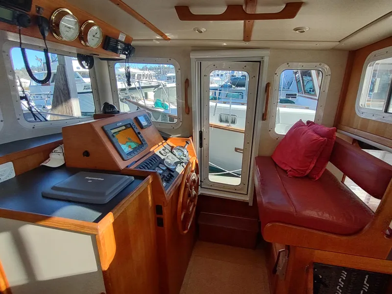 Slide: The Image of 2006 Nordic Tug 32 interior with helm, navigation equipment, and red seating. - 36