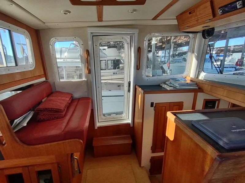 Slide: The Image of Interior of a 2006 Nordic Tug 32 boat with red seating and wooden cabinetry. - 37