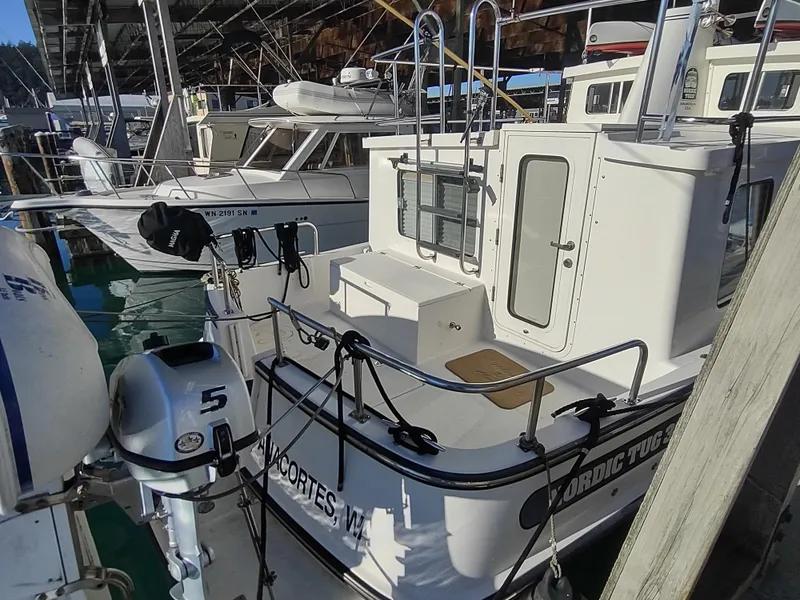 Slide: The Image of 2006 Nordic Tug 32 docked in a marina, featuring a white exterior and visible outboard motor. - 7