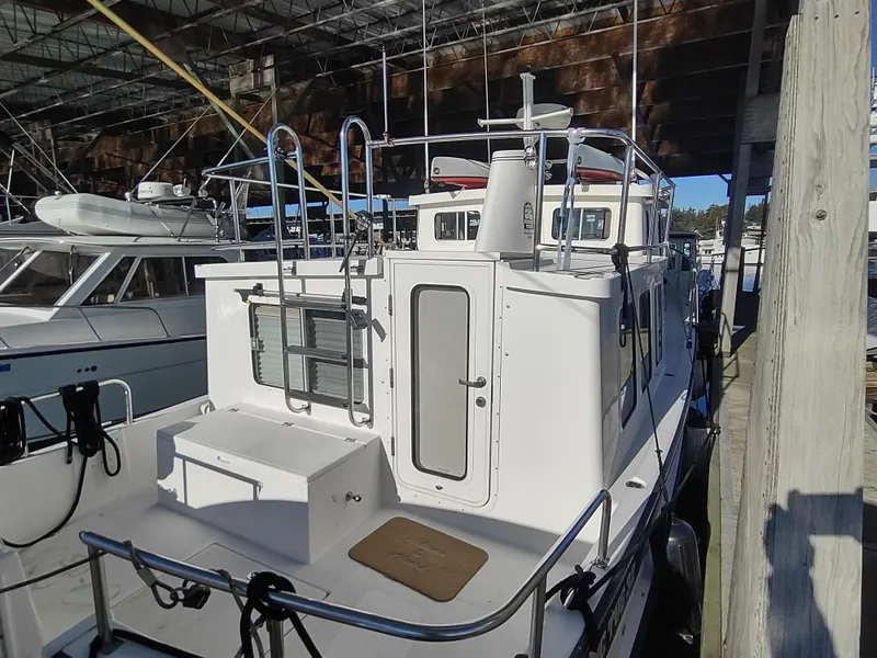 Slide: The Image of 2006 Nordic Tug 32 docked in a marina, showcasing its rear deck and cabin entrance. - 9