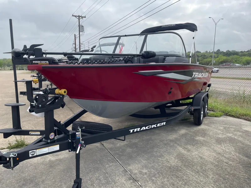Slide: The Image of 2025 Tracker Targa V-18 Combo boat on trailer, red exterior, parked outdoors. - 2