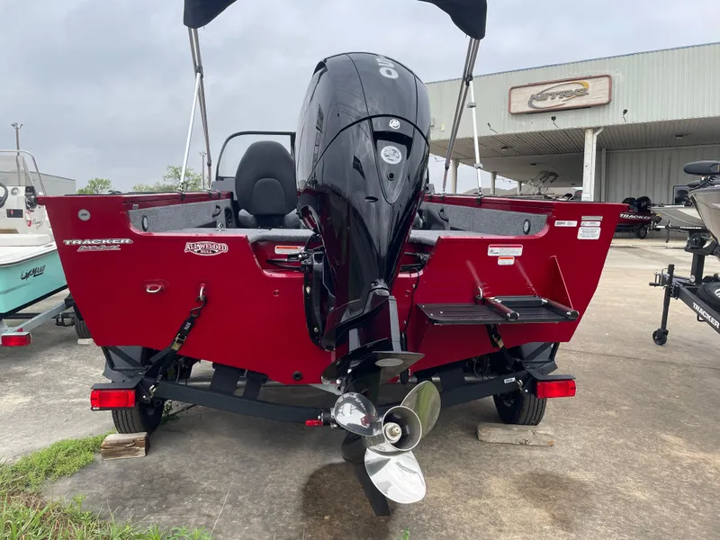 Slide: The Image of 2025 Tracker Targa V-18 Combo boat, red exterior, displayed outdoors with motor. - 5