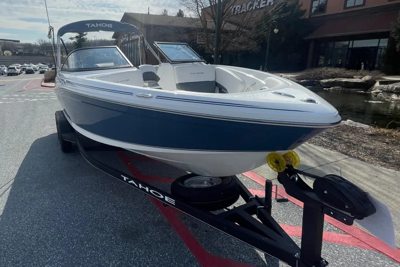 Slide: The Image of 2024 Tahoe 210 S boat on trailer, parked outdoors near buildings. - 2