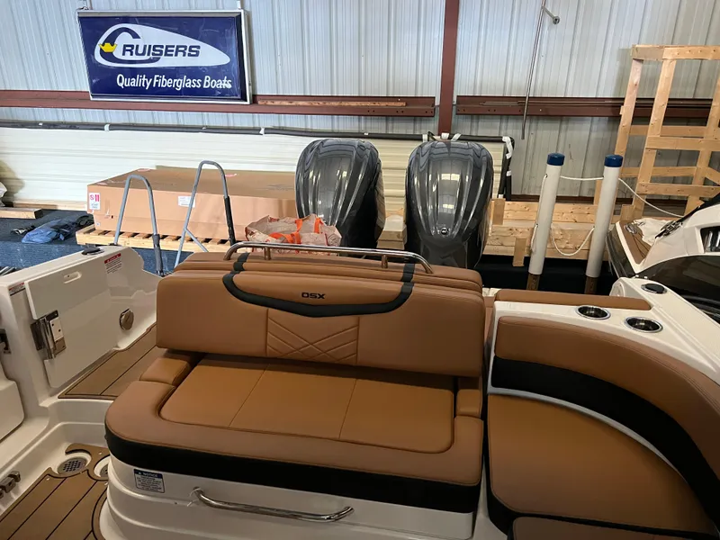 Slide: The Image of 2023 Chaparral 280 OSX boat interior with tan seating and dual engines in a showroom. - 3