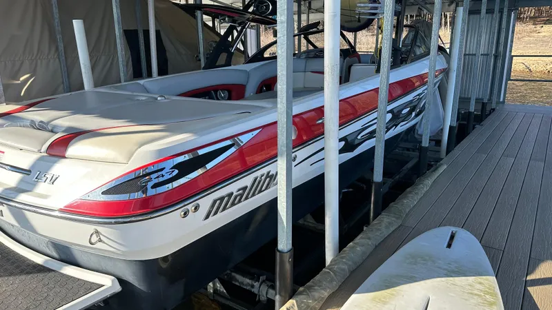 Slide: The Image of 2007 Malibu 247LSV boat docked, featuring red and white design. - 12