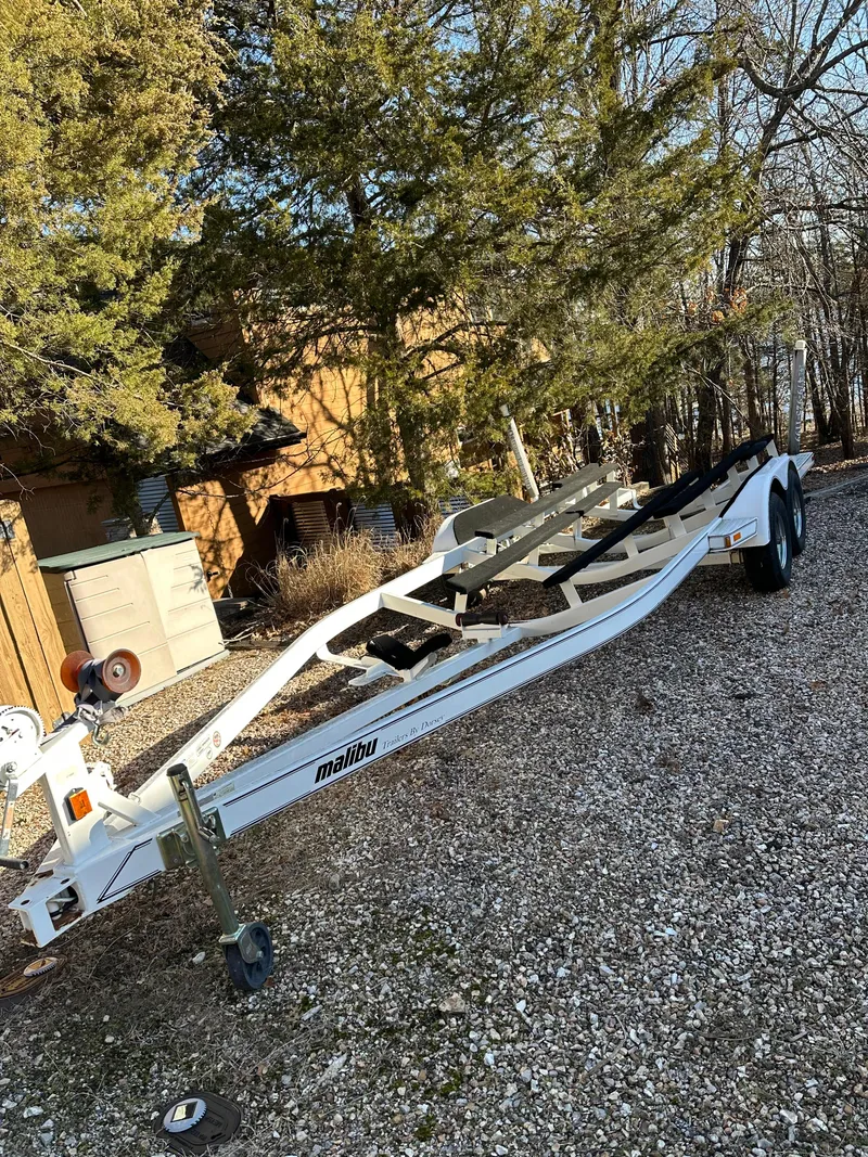 Slide: The Image of White 2007 Malibu 247LSV boat trailer parked on gravel near trees. - 13