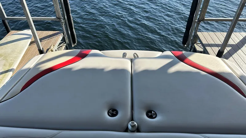 Slide: The Image of Rear view of a 2007 Malibu 247LSV boat with red accents, docked by the water. - 4