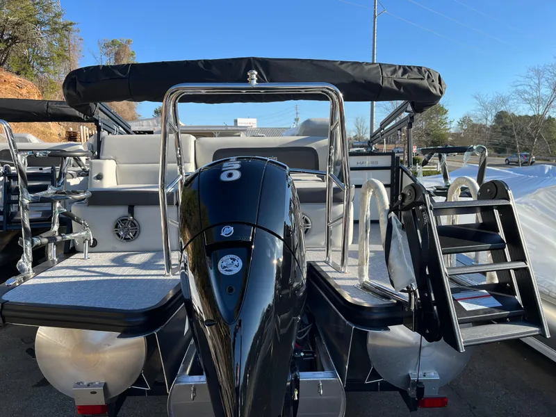 Slide: The Image of 2025 Harris Cruiser 230 pontoon boat with outboard motor, rear view, docked outdoors. - 8