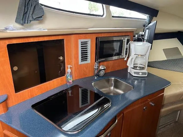 Slide: The Image of 2006 Bayliner 275 boat interior kitchen with sink, stove, microwave, and coffee maker. - 15