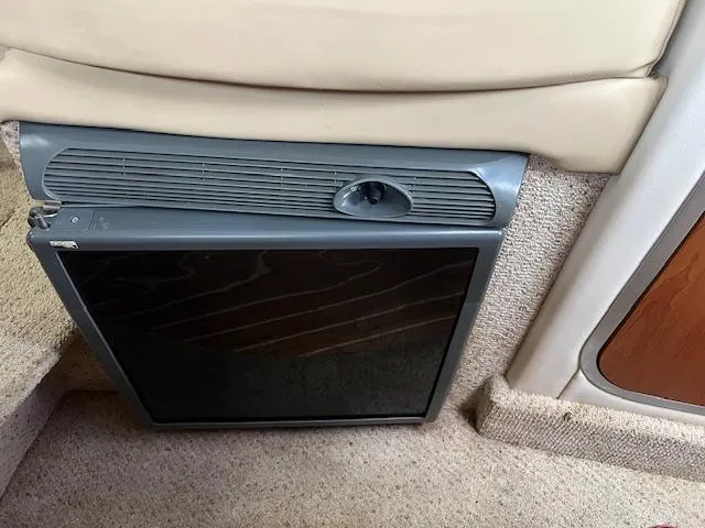 Slide: The Image of 2006 Bayliner 275 interior with built-in mini fridge and beige upholstery. - 16