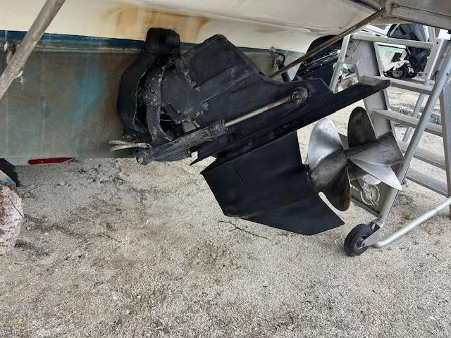Slide: The Image of 2006 Bayliner 275 boat propeller and outdrive on sandy ground. - 7