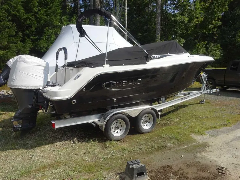 Slide: The Image of 2023 Robalo R227 boat on trailer, black hull, covered, parked outdoors. - 3