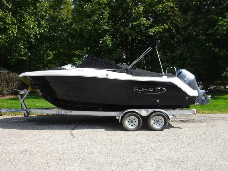 Slide: The Image of 2023 Robalo R227 boat on trailer, black hull, parked outdoors. - 4