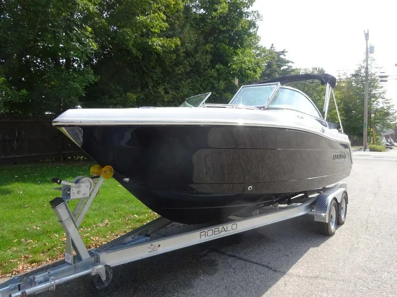 Slide: The Image of 2023 Robalo R227 boat on trailer, parked on a street with greenery. - 5