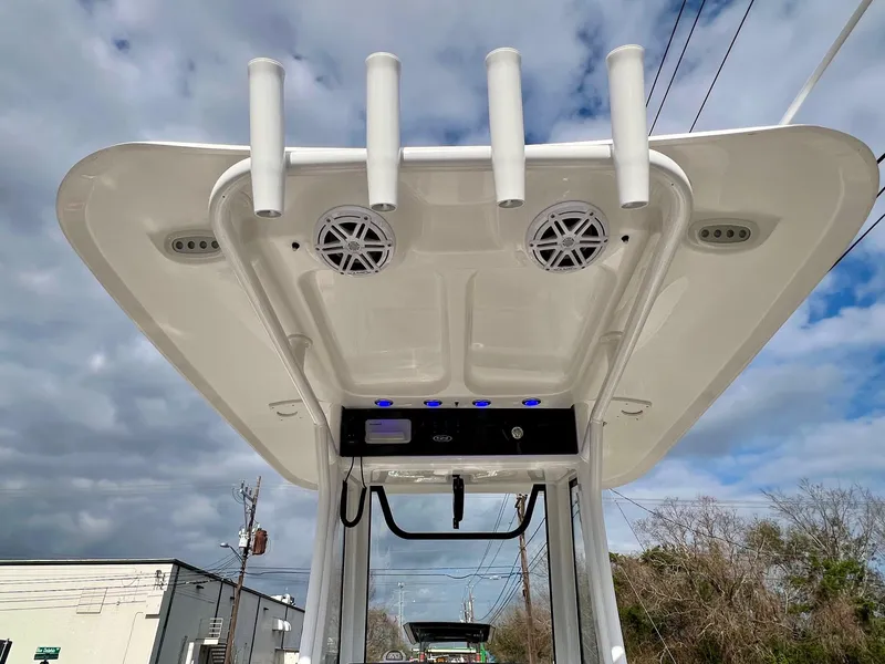 Slide: The Image of 2025 Sea Hunt Ultra 235 SE boat T-top with rod holders and speakers under cloudy sky. - 10