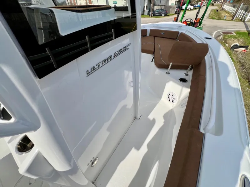 Slide: The Image of 2025 Sea Hunt Ultra 235 SE boat interior with brown seating and sleek white design. - 14
