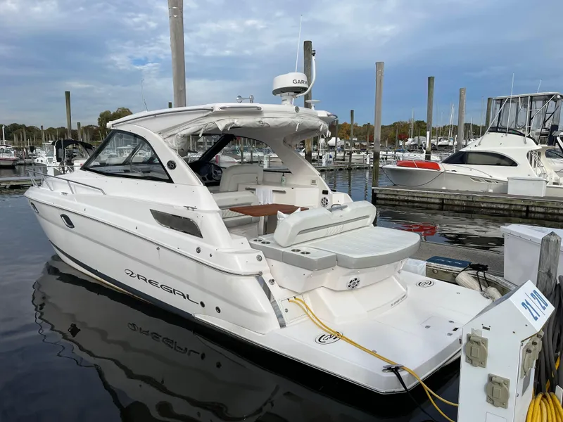 Slide: The Image of 2021 Regal 35 Sport Coupe boat docked at marina, featuring sleek white design. - 2