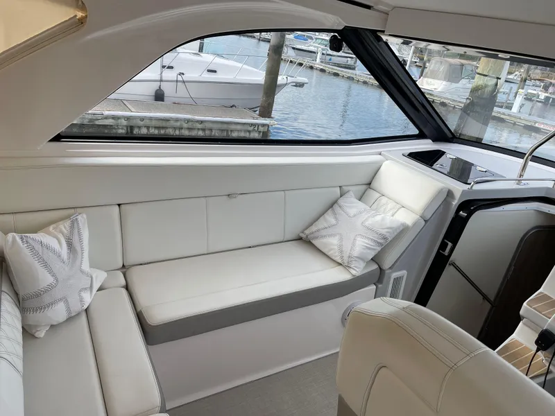 Slide: The Image of 2021 Regal 35 Sport Coupe interior with white seating and marina view. - 28