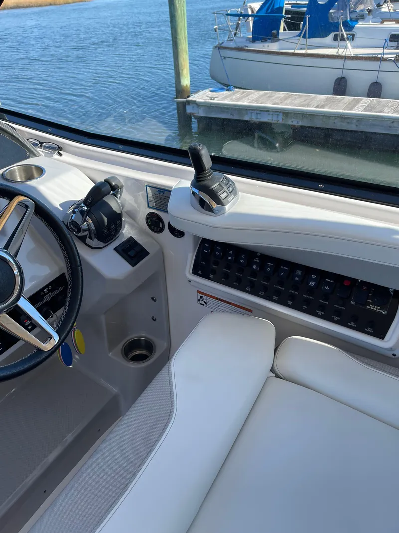 Slide: The Image of 2021 Regal 35 Sport Coupe cockpit with steering wheel and control panel, docked by the water. - 31