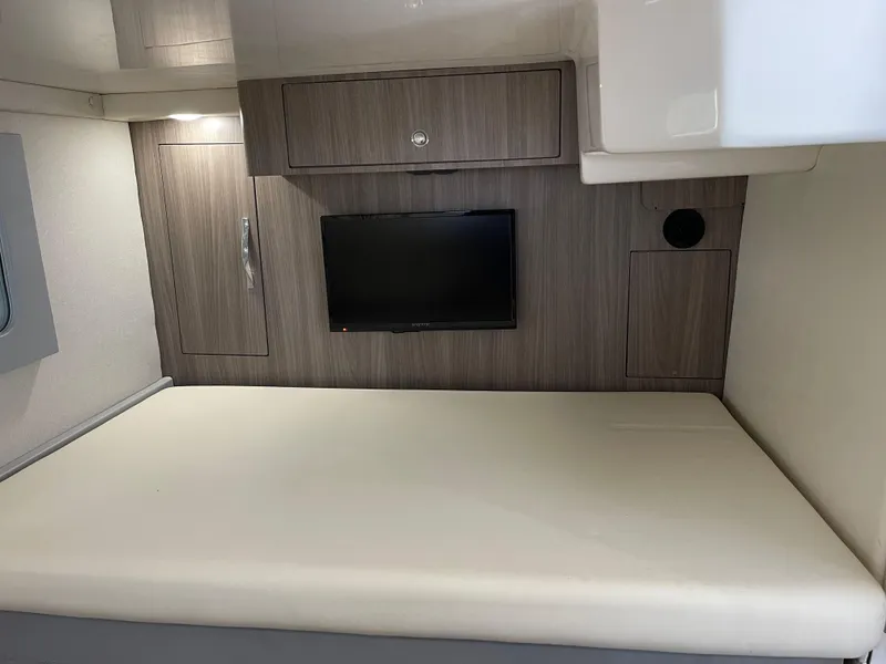 Slide: The Image of 2021 Regal 35 Sport Coupe interior cabin with bed, TV, and wooden cabinetry. - 44