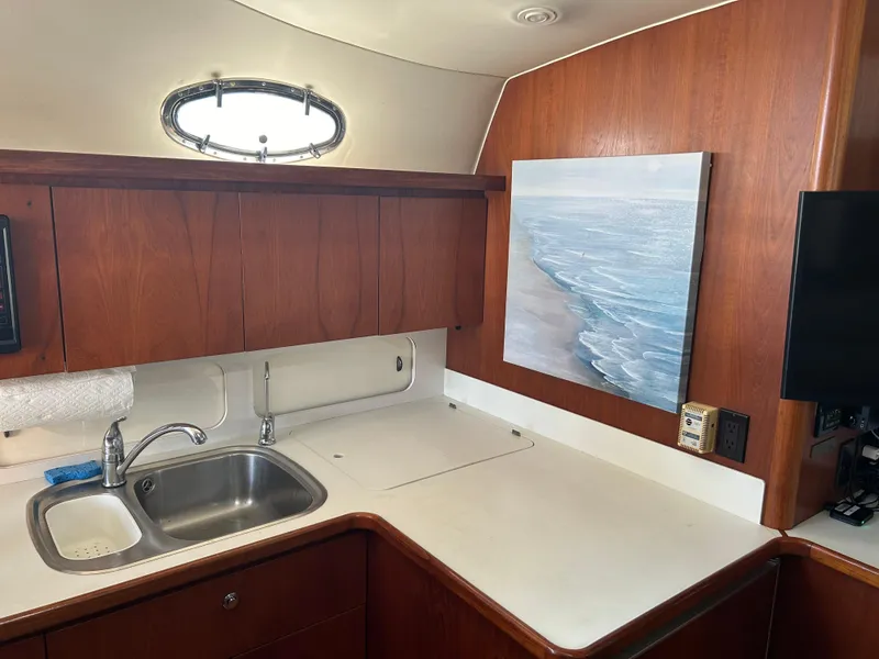 Slide: The Image of 1997 Tiara Yachts 4000 Express interior kitchen with sink, wooden cabinets, and ocean artwork. - 30