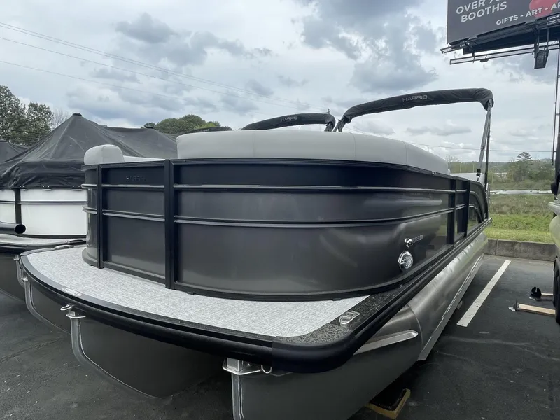 The Image of 2025 Harris Cruiser 230 pontoon boat in a parking lot under cloudy skies. - 0