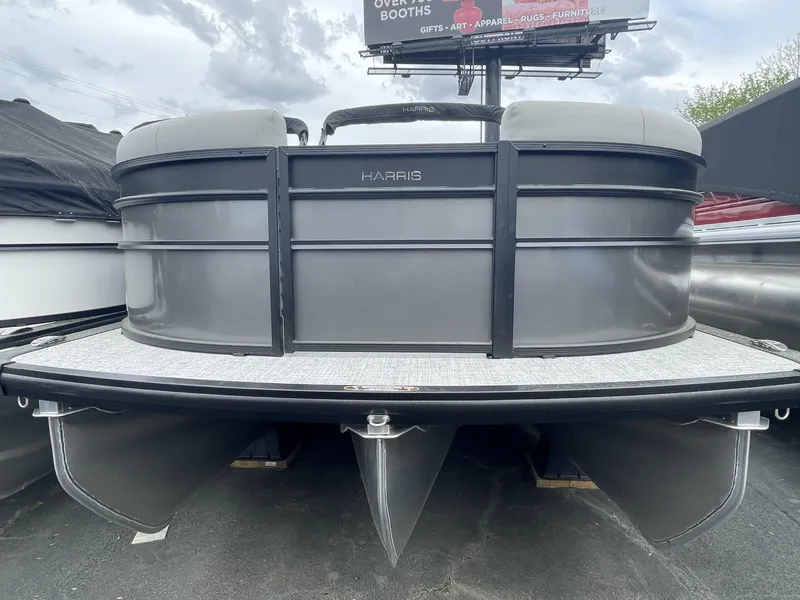 Slide: The Image of 2025 Harris Cruiser 230 pontoon boat, gray exterior, docked under cloudy sky. - 1