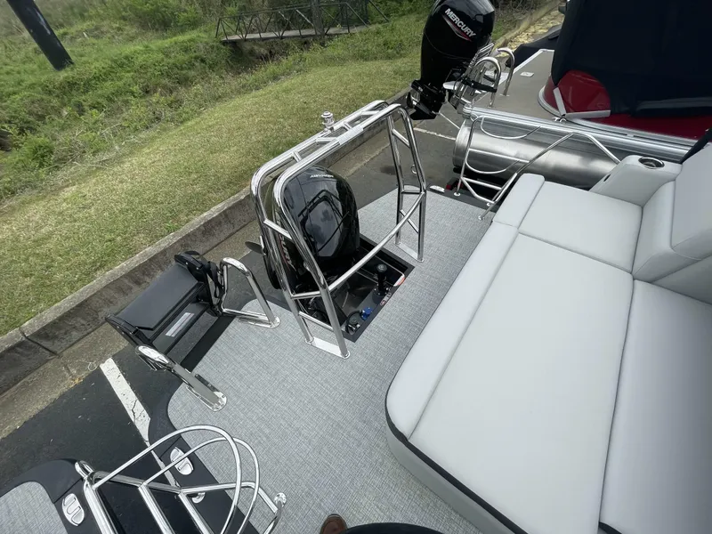 Slide: The Image of 2025 Harris Cruiser 230 boat interior with seating and motor, parked on a grassy area. - 15