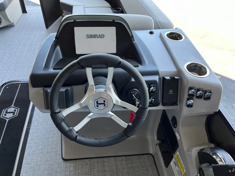 Slide: The Image of 2025 Harris Cruiser 230 boat dashboard with steering wheel and Simrad display. - 18