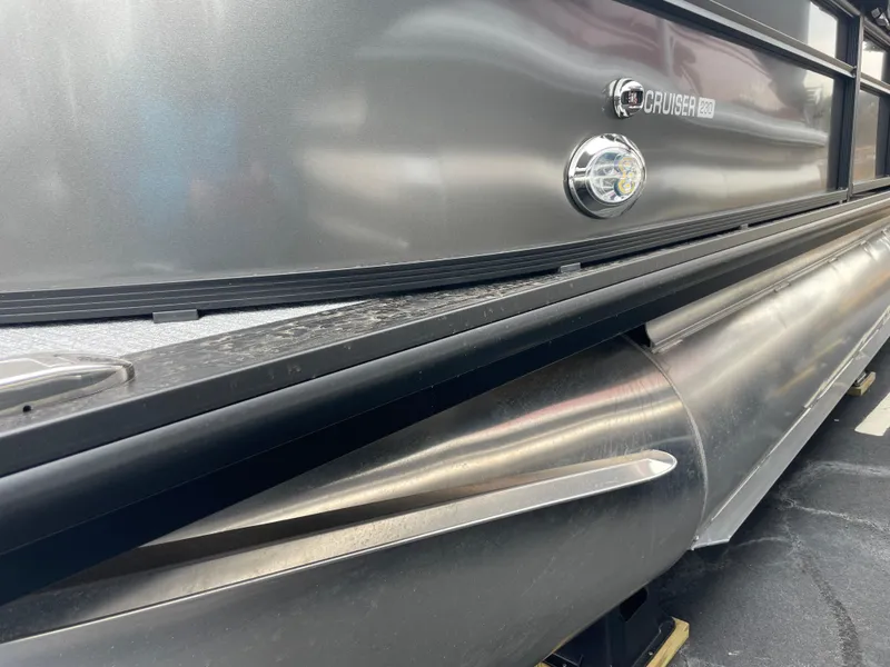 Slide: The Image of 2025 Harris Cruiser 230 pontoon boat, sleek metallic finish, close-up view. - 2