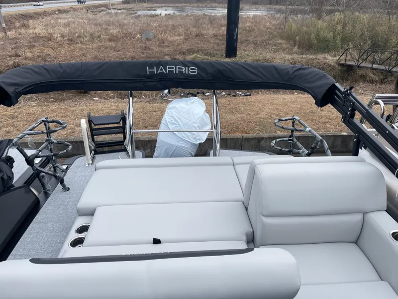 Slide: The Image of 2025 Harris Cruiser 230 boat with sleek seating and canopy, docked outdoors. - 6