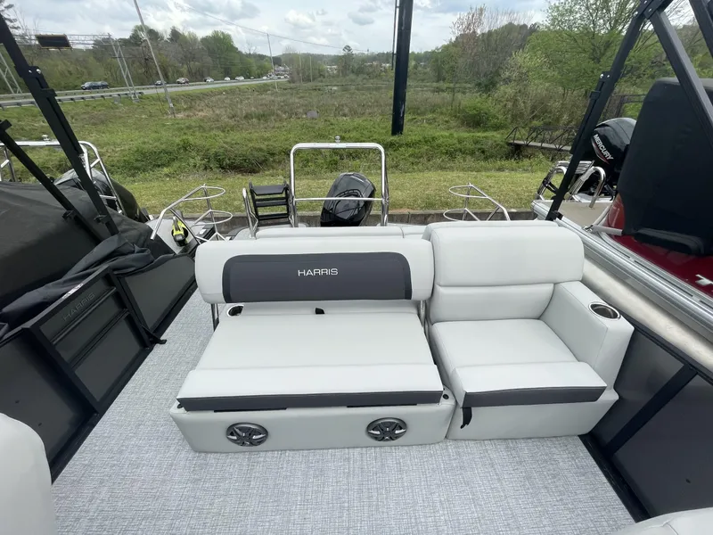 Slide: The Image of 2025 Harris Cruiser 230 boat interior with white seating and speakers, set against a natural backdrop. - 7