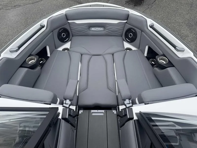 Slide: The Image of 2025 Supra SL boat interior with gray seating, cup holders, and speakers. - 14