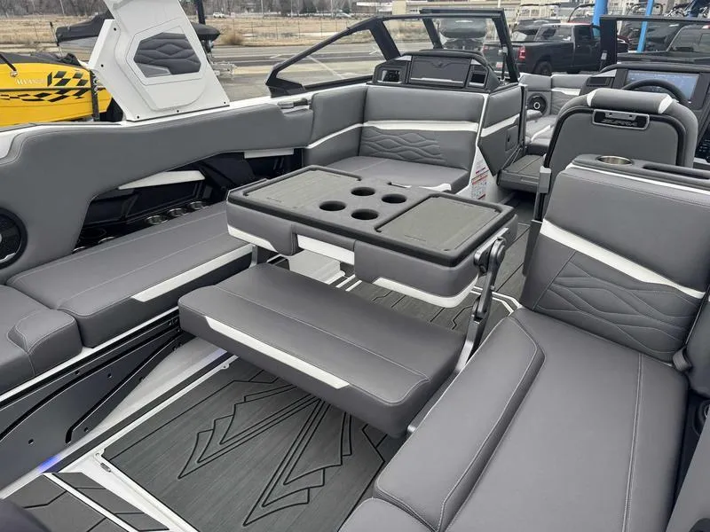 Slide: The Image of 2025 Supra SL boat interior with gray seating and a central table featuring cup holders. - 18