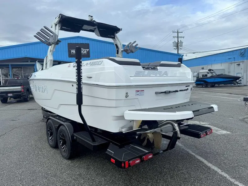Slide: The Image of 2025 Supra SL boat on trailer, parked outdoors near blue building. - 5