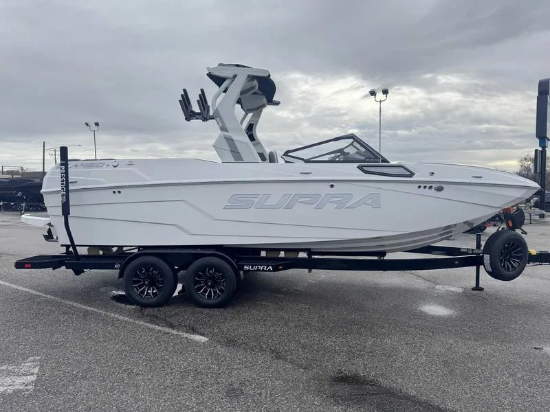 Slide: The Image of 2025 Supra SL boat on trailer in parking lot, overcast sky. - 6