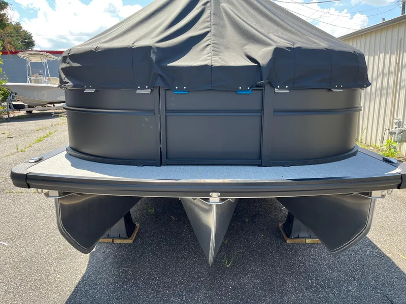 Slide: The Image of 2025 Harris Cruiser 230 pontoon boat with cover, parked outdoors on pavement. - 2