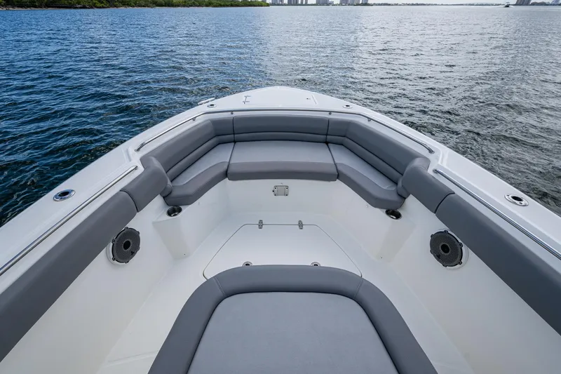 Slide: The Image of 2023 Boston Whaler 330 Outrage boat interior with cushioned seating on calm water. - 25
