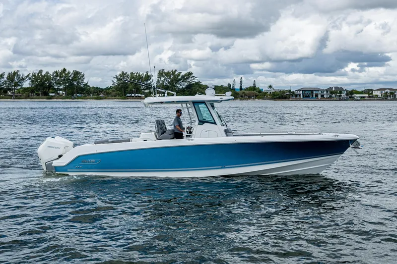 Slide: The Image of 2023 Boston Whaler 330 Outrage boat cruising on a calm waterway under cloudy skies. - 3