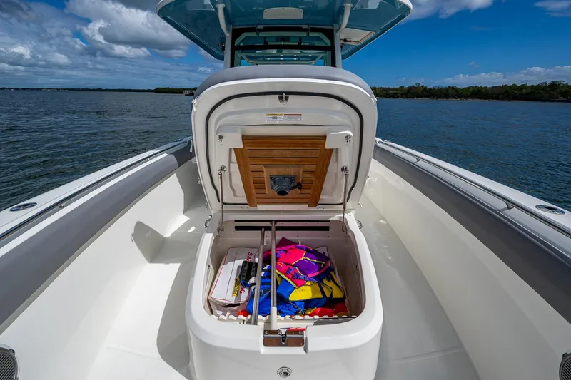 Slide: The Image of 2023 Boston Whaler 330 Outrage boat with open storage compartment, colorful gear inside. - 31