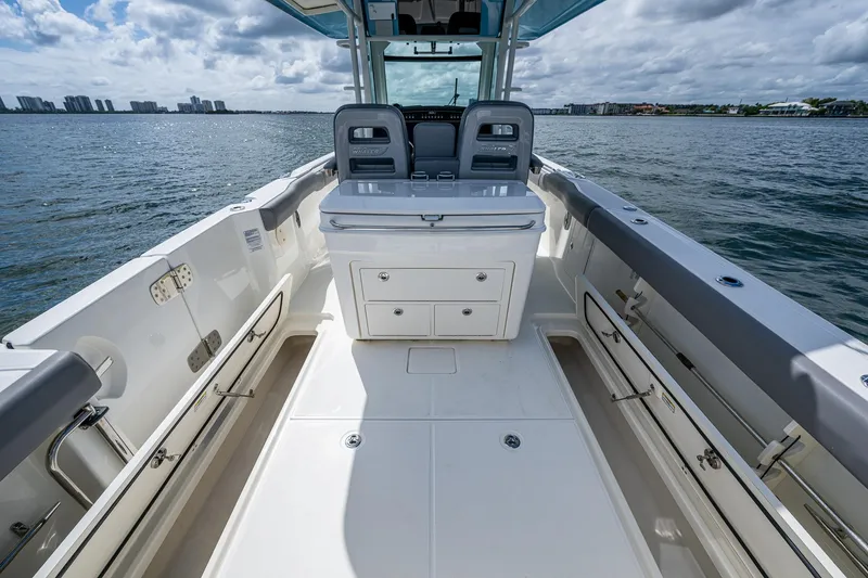 Slide: The Image of 2023 Boston Whaler 330 Outrage boat interior with seating and storage, on calm water. - 37