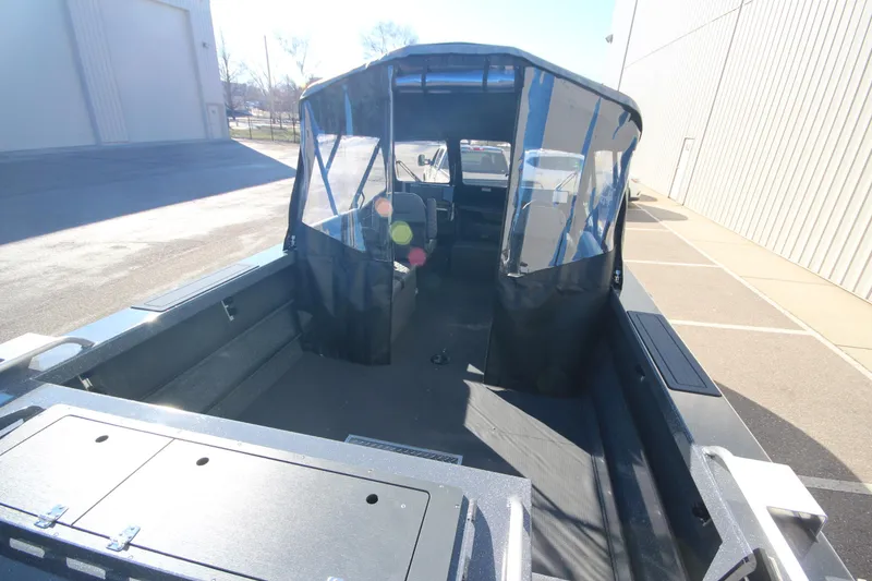 Slide: The Image of 2025 Weldcraft 210 Revolution Soft Top boat, spacious interior, parked outdoors. - 12