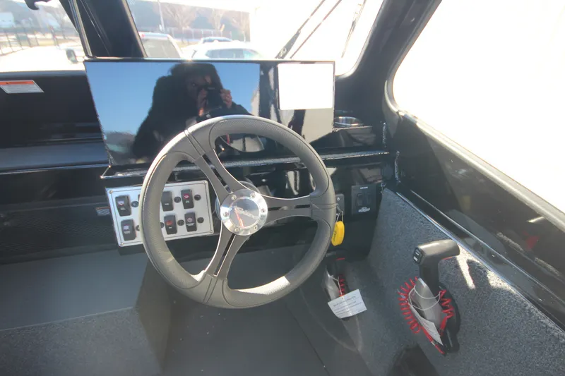 Slide: The Image of Interior of 2025 Weldcraft 210 Revolution boat, featuring steering wheel and control panel. - 23