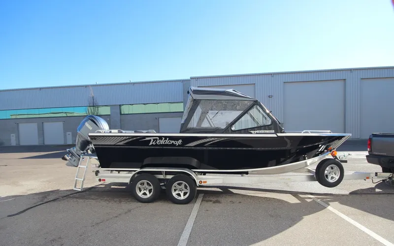 Slide: The Image of 2025 Weldcraft 210 Revolution Soft Top boat on trailer, parked outdoors. - 3