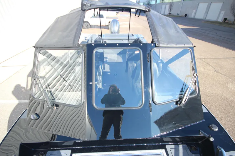 Slide: The Image of 2025 Weldcraft 210 Revolution Soft Top boat with reflective windows and sleek design. - 34