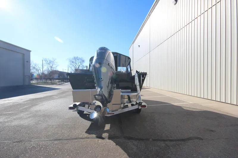 Slide: The Image of 2025 Weldcraft 210 Revolution Soft Top boat, rear view, parked outside a warehouse. - 8