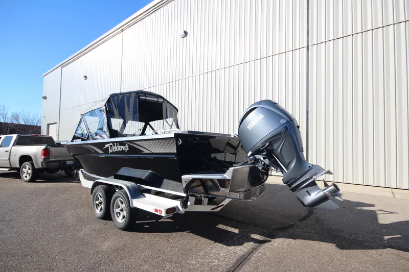 Slide: The Image of 2025 Weldcraft 210 Revolution Soft Top boat with F200XB engine, parked outside a building. - 9