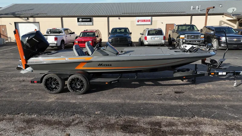 Slide: The Image of 2024 iKon LX20 boat on trailer, parked in lot with vehicles in background. - 4
