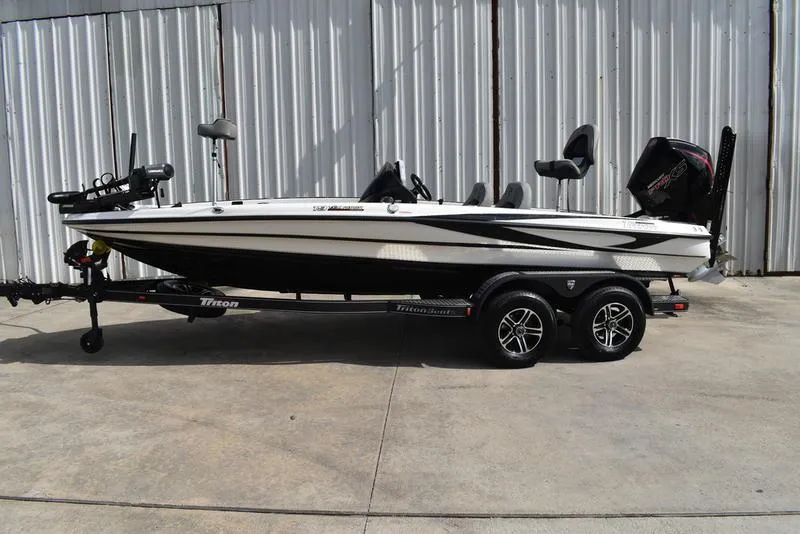 Slide: The Image of 2025 Triton 19 TrX Patriot boat on trailer, parked outdoors. - 2