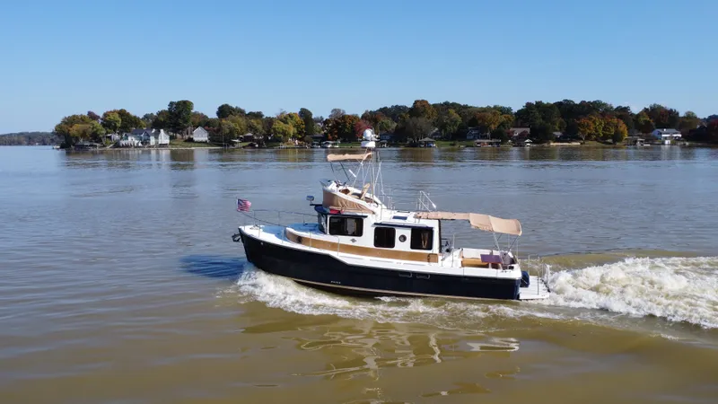 Slide: The Image of 2014 Ranger Tugs R-31CB cruising on a calm lake with scenic shoreline. - 0
